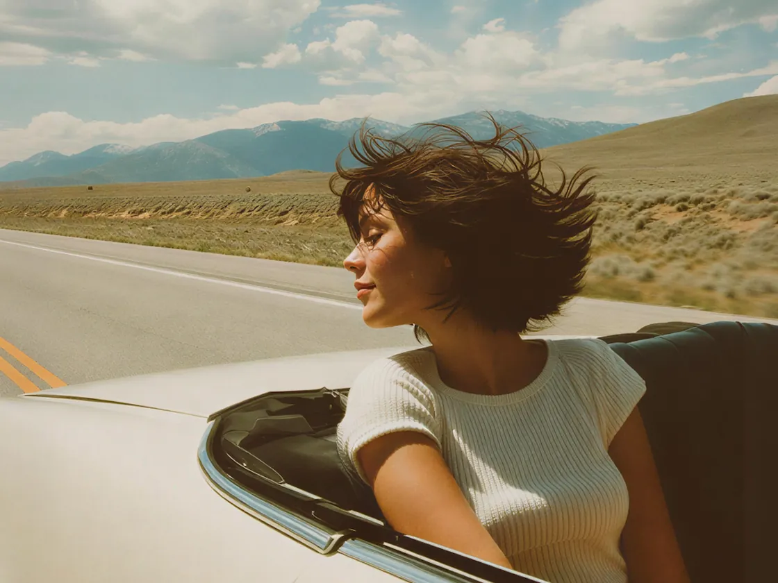 Woman driving a white convertible on an open={true} desert road
